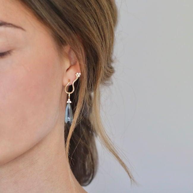 Ro Copenhagen 18kt Fryd Wave diamanten oorbellen tonen een elegante gouden oorbel met diamanten op het oor, model 108105-2.