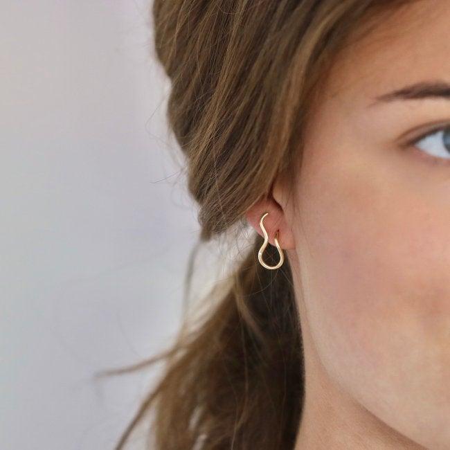 Ro Copenhagen In het linkeroor zijn 18kt Fryd Wave-oorbellen te zien, elegant in golfvormig goud. Model 108102-2