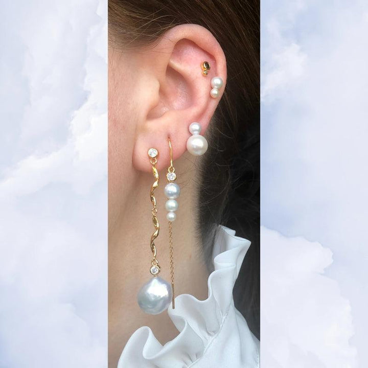 Nuit Hook Threader Kaede Earring met gouden details en witte parels wordt op het oor gedragen. ModelSS2220-2