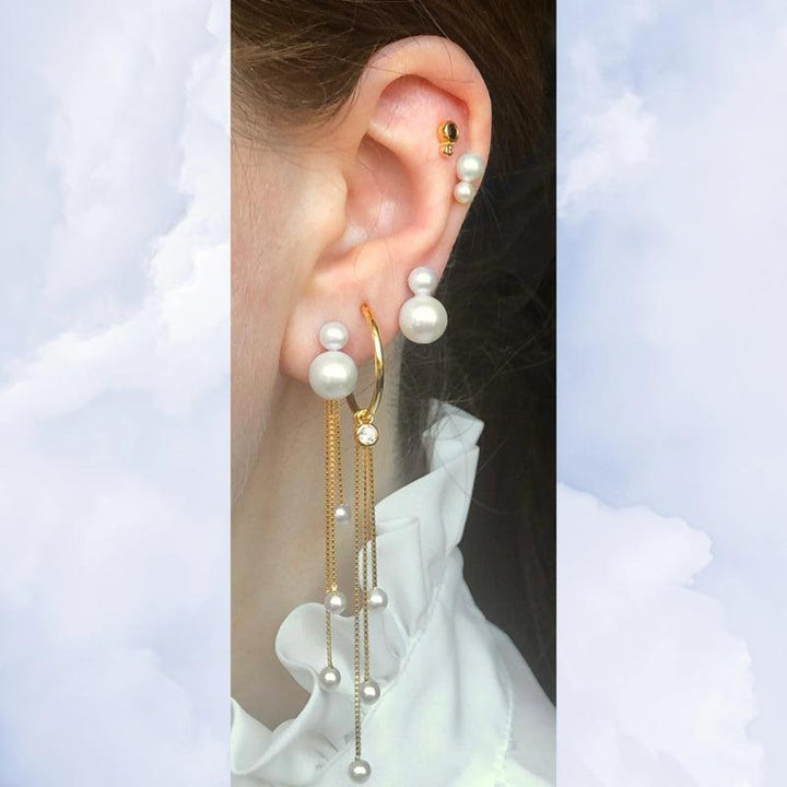 Tassel Pearl Charm SS2223 toont een oor met gouden oorbel, witte parels en lange gouden kettingen. ModelSS2223-2